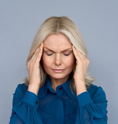 Stressed frustrated middle aged lady suffering from headache massaging temples, close up view. Tired sick mature old woman feeling unwell, touching head. Migraine pain, fatigue, stress concept